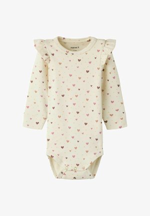 Crèmekleurige baby romper met roze en bruine hartjes, lange mouwen, schoudervolants en drukknopen aan de onderkant.