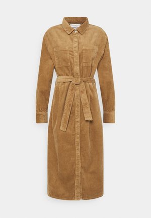 Lang kamel-farvet kordfløjls kjole med lange ærmer, knaplukning foran, brystlommer, krave og matchende stofbælte bundet i taljen.