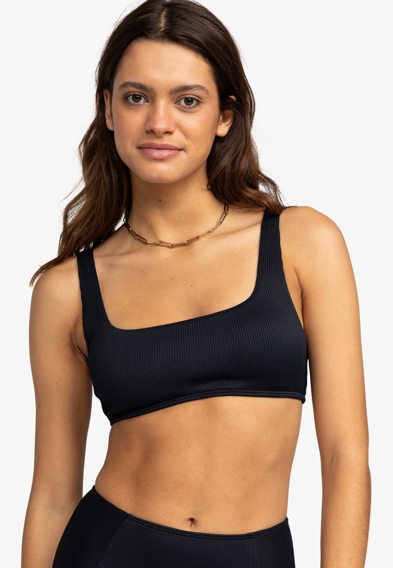 Top sportivo nero a costine con scollatura quadrata e spalline larghe. Presenta una texture liscia e un design minimalista, adatto per l'abbigliamento attivo.