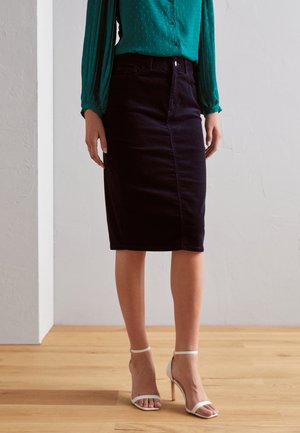 Donker denim kokerrok met een rechte pasvorm, voorzien van een voornaad en een tailleband. Gecombineerd met witte sandalen met bandjes en een tealblauwe blouse.