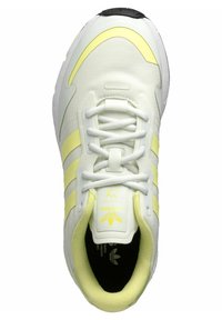 Balti sporta apavi ar dzelteniem akcentiem, aprīkoti ar auklām, trīs svītru dizainu un mīksto zoli. Uz valkāšanas daļas redzams teksts "adidas".