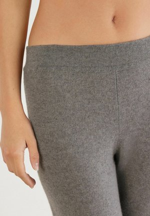 Leggings gris en tricot avec une large ceinture côtelée. La texture est douce et lisse, montrant un gros plan du tissu sans détails supplémentaires.
