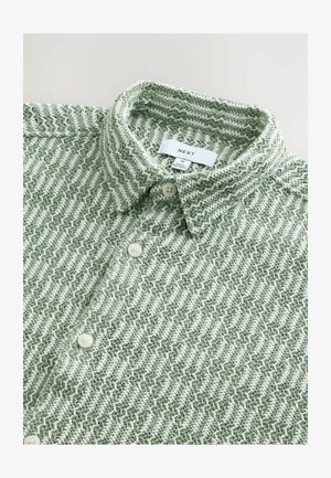 Roheline ja valge siksakmustriga särk, millel on kraega kaelus, nööbid ja pehme, tekstureeritud kangas. Brändi silt on nähtav.