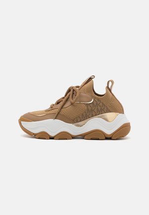 Beige Sport Schuhe verfügen über ein Mesh-Obermaterial, eine abgerundete weiße Zwischensohle, eine Gummisohle und kontrastierende goldene Akzente mit einem Markenlogo.