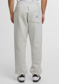 Helle graue Jogginghose mit relaxed Fit, elastischem Bund und einer Gesäßtasche mit einem kleinen Logostick. Hergestellt aus weichem, strukturiertem Stoff.