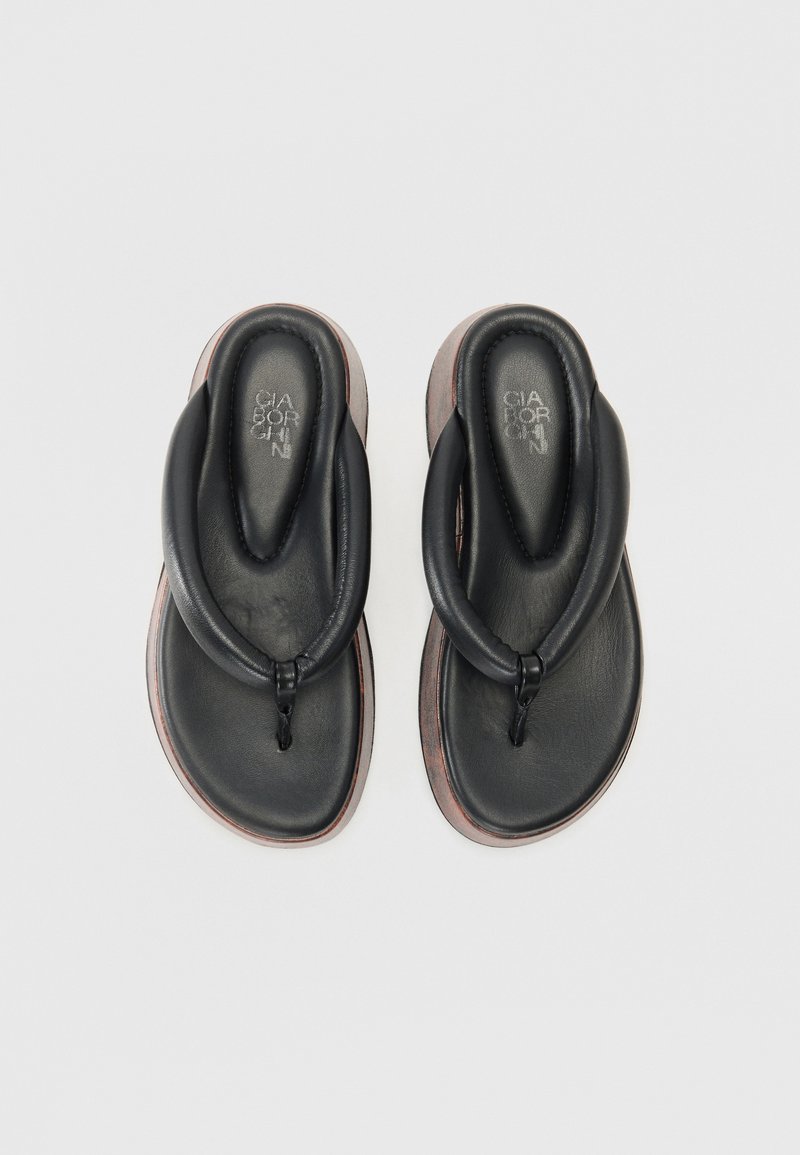 Svarta läderflip-flops med knuten remdesign, som har en vadderad fotbädd och kontrasterande bruna sula kanter. Slät yta.