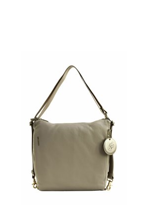 Sac à épaule en cuir beige avec une large bandoulière et un charm rond avec logo attaché sur le côté.