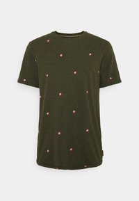 Olivengrøn t-shirt med korte ærmer, prydet med spredte lyserøde polka prikker. Den er lavet af blødt stof, har en rund halsudskæring og en lige kant.