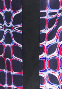 Tištěná tkanina s barevným vzorem, obsahující červené, modré a bílé tvary, v kontrastu s pevným černým bočním panelem. Texturovaný povrch.