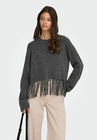 Pelēks apgrieztais džemperis ar fringēm ap apakšu, izgatavots no strukturēta adījuma. Garas piedurknes un apaļa kakla izgriezums. Pāris ar gaišiem biksēm.