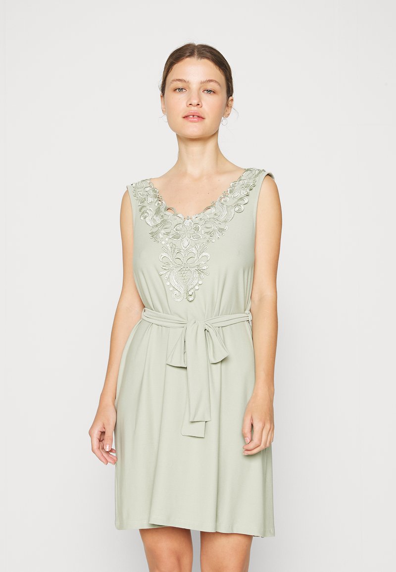 Vestido sem mangas de verde claro com decote em V bordado, cintura ajustada com fita e saia fluida. Tecido suave com textura lisa.