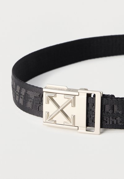 Μαύρη υφασμάτινη ζώνη με υφή και ασημί ορθογώνια αγκράφα που διαθέτει τέσσερα βέλη που δείχνουν προς τα έξω.