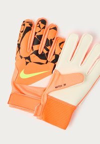 Guantes de portero Nike en color naranja brillante con patrones geométricos en negro. Superficie de agarre texturizada, palma blanca y banda elástica en la muñeca. Modelo: MATCH JR.