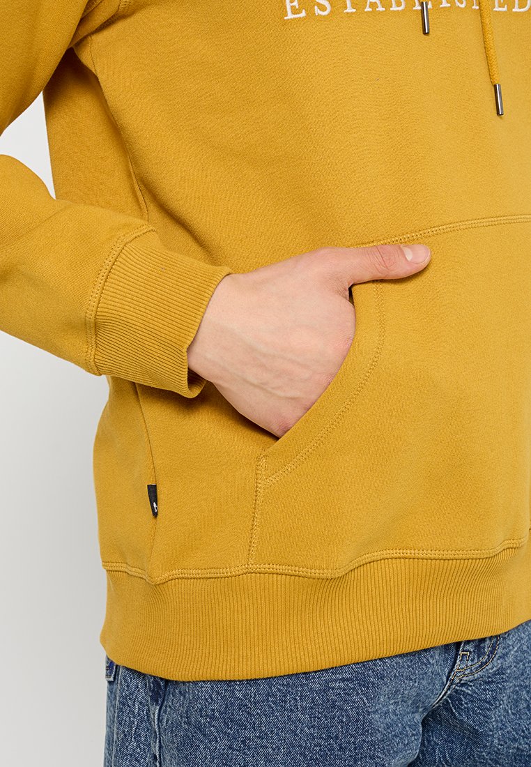 Felpa gialla con tasca frontale, polsini e orlo a costine. Caratterizzata da un logo stampato in bianco sul petto. Tessuto morbido e testurizzato.