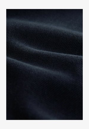 Marineblauer Stoff mit einer strukturierten Webart, der sanfte Falten und eine glatte Oberfläche zeigt, die das Licht auf subtile Weise reflektiert.