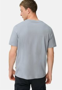 Lys grå kortærmet t-shirt lavet af blødt stof. Har en rund halsudskæring og et enkelt design uden synlige logoer eller mønstre.
