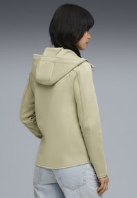 Felpa verde chiaro con finitura testurizzata, cordino regolabile e maniche lunghe, abbinata a pantaloni in denim blu chiaro.