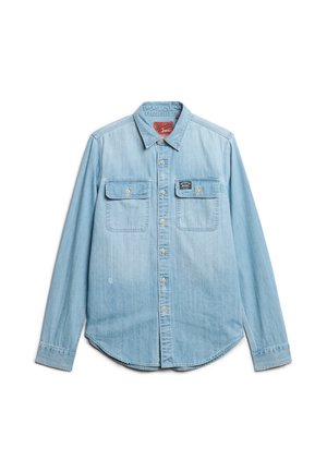 Lyseblå denimskjorte med lange ærmer, to brystlommer og en spids krave. Har metalknapper og en rund kant.