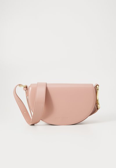 Sac cabas en cuir rose avec une forme arrondie, ferrures dorées et une longue bandoulière. Texture lisse avec un logo de marque subtil embossé.
