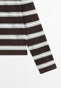 Langærmet del af en stribet skjorte med vandrette bånd i sort, grå og hvid, vist mod en hvid baggrund.