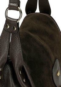 Ciemnobrązowa torba z zamszu i skórki o fakturze kamienia, z okrągłymi uchwytami, metalowymi pierścieniami, nitami oraz małym złotym trójkątnym detalem z logo.