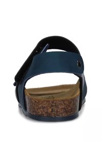 Sandalo blu con intersuola in sughero e cinturini neri. Caratterizzato da chiusura regolabile e texture liscia sulla parte superiore. Design leggero e minimalista.