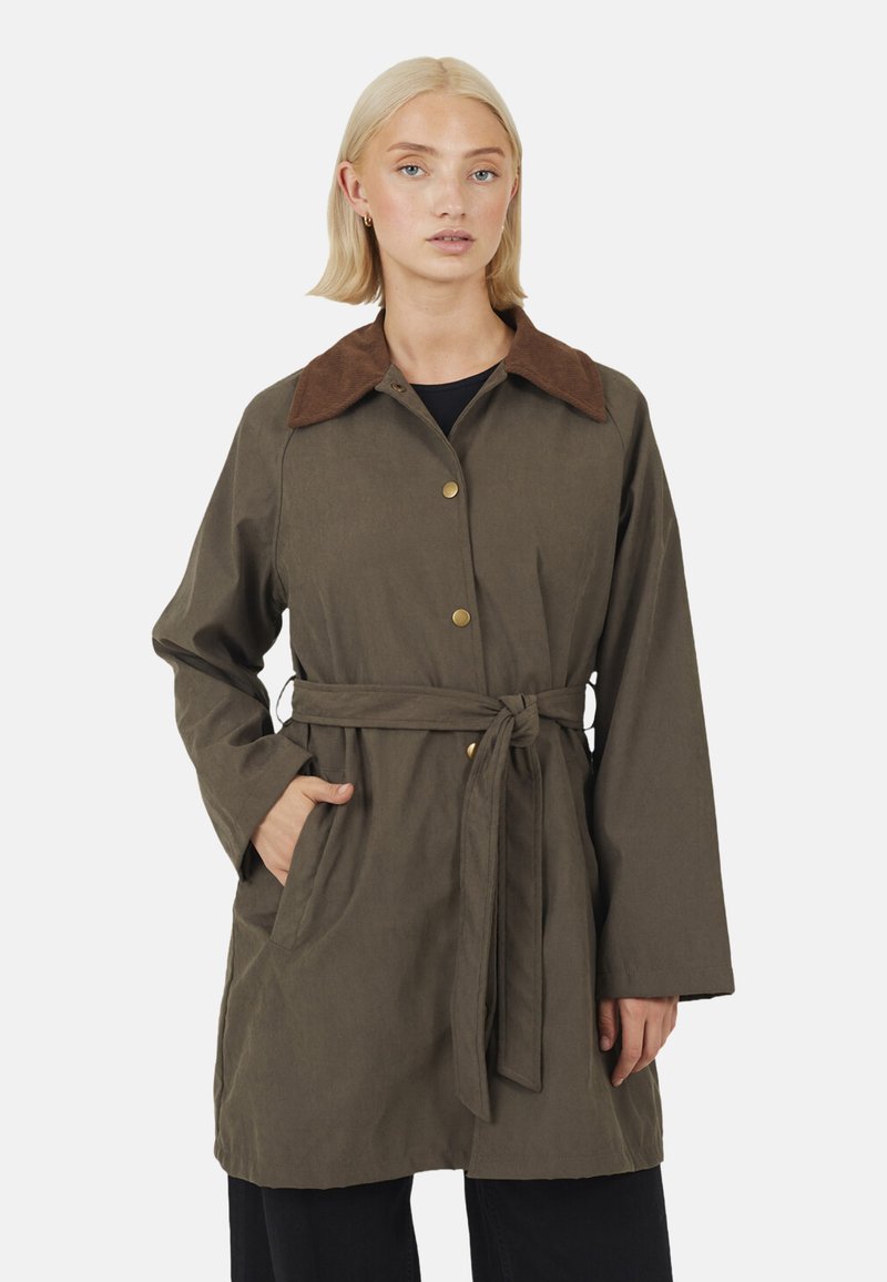 Cappotto verde oliva con cinturetta e collo marrone, caratterizzato da maniche lunghe, chiusura con bottoni e tasche laterali. Tessuto morbido e testurizzato.