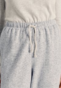 Light gray sweatpants with a soft, textured fabric feature a drawstring waist and relaxed fit, emphasizing comfort and casual style.