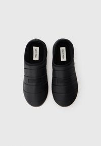 Pantofi slip-on negri, căptușiți, cu suprafață texturată și margini elasticizate. Prezintă detalii cu logo pe parte superioară și căptușeală interioară moale pentru confort.
