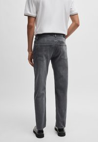 Grå denim jeans med lige pasform, baglommer og subtilt falmet tekstur, parret med en hvid polo shirt med stribede detaljer.