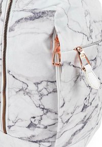 Mochila con diseño de mármol blanco que presenta un cierre y herrajes en tono dorado, con un bolsillo lateral y una textura de tela suave.