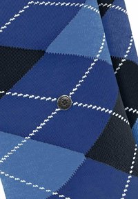 Tissu à motif argyle bleu présentant différentes nuances de bleu et de noir. Comprend un détail en métal argenté au centre. Tricot texturé.