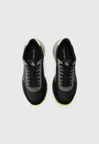 Zwarte en grijze sneakers met textiel stof en gladde accenten. Heeft een neon groene zool en een gepersonaliseerd interieur. Standaard vetersluiting.