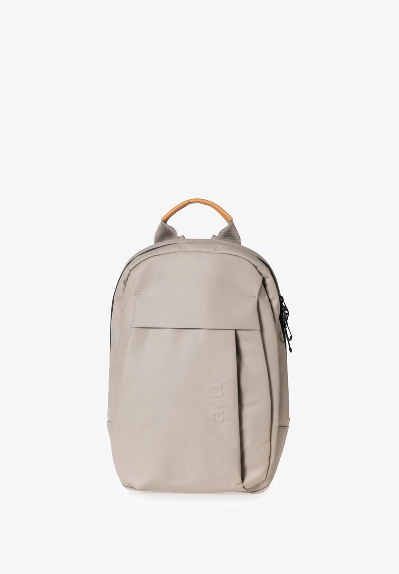 Zaino grigio chiaro con finitura testurizzata, dotato di manico in pelle sulla parte superiore, tasca frontale e spallacci regolabili. Chiusura con zip.