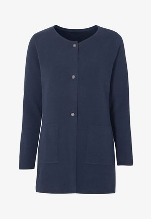 Navyblauwe cardigan gemaakt van een geweven stof, met een ronde halslijn, metalen knopen en twee voorkruiden. De lengte komt tot halverwege de heup.