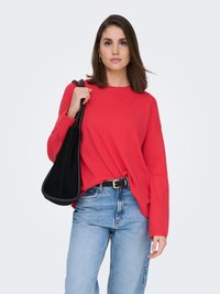 Haut à manches longues rouge, coupe décontractée, associé à un jean droit bleu clair. Accessoire comprenant un sac à bandoulière noir. Design simple, sans motifs.