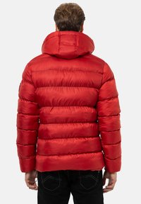 Rote Pufferjacke mit hohem Kragen, gestepptem Design und glänzender Oberfläche. Besitzt eine lockere Passform und elastische Bündchen für zusätzliche Wärme.
