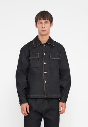 Donkerdenim jack met contrasterende gele stiksels, twee voorzakken en metalen drukknoopjes. Boxy silhouet met een kraag.