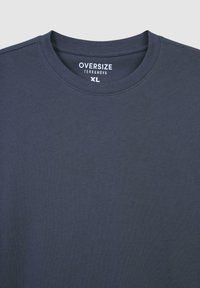 T-shirt oversize di colore blu scuro in morbido cotone, con una superficie liscia, collo rotondo e etichetta "Terranova XL" all'interno.