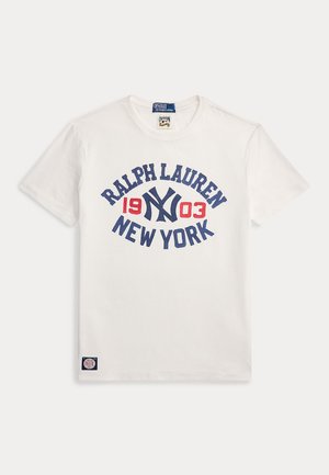 T-shirt en coton blanc avec un texte graphique bleu et rouge "RALPH LAUREN 1903 NEW YORK" dans un design circulaire. Comprend une petite étiquette logo.