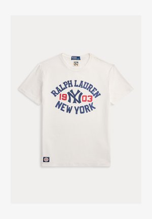 T-shirt en coton blanc avec un texte graphique bleu et rouge "RALPH LAUREN 1903 NEW YORK" dans un design circulaire. Comprend une petite étiquette logo.