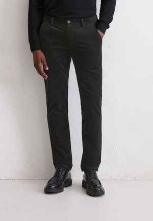 Zwarte corduroy broek met een recht model, voorzien van voorzakken en een knoopsluiting, gecombineerd met zwarte veterschoenen.