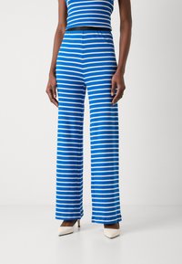Blå- och vitrandig stickad jumpsuit med vida ben, som har ett elastiskt midjeband och en figurnära överdel. Texturen är mjuk och stretchig.