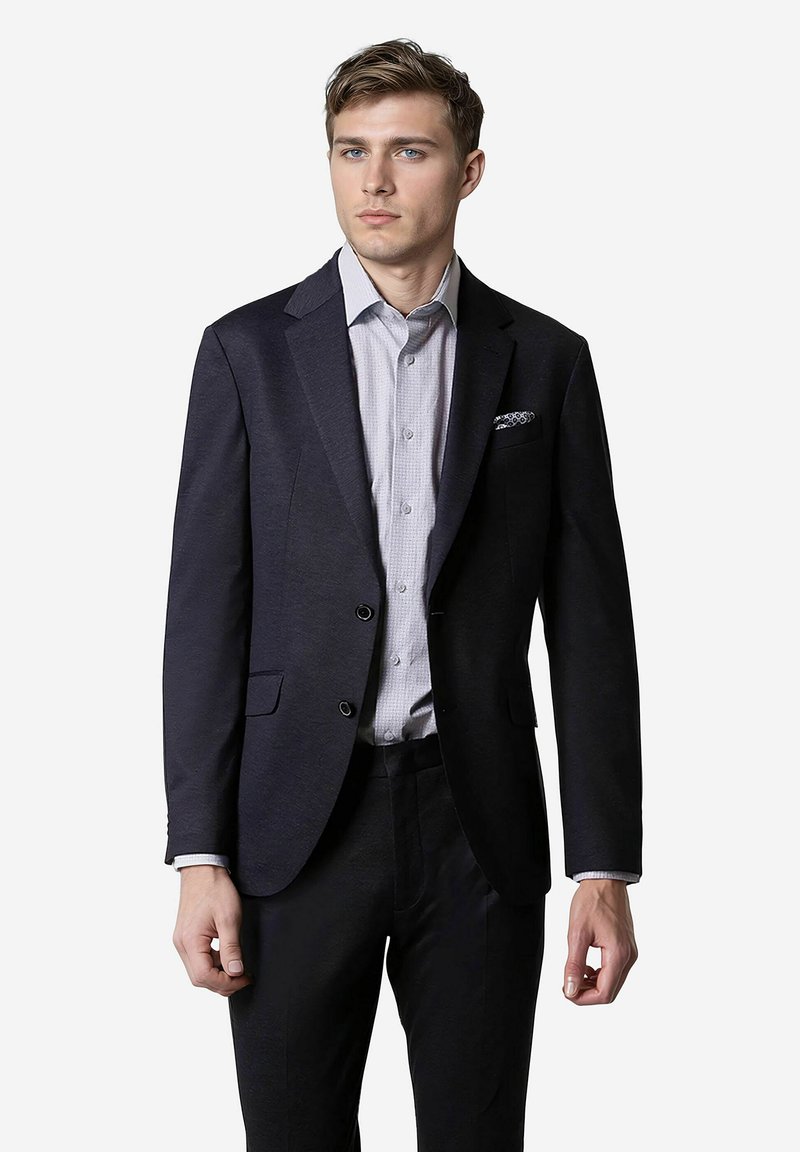 Ciemnoniebieski marynarka z dwoma guzikami, klapami w kształcie notcha oraz lekko teksturowana, w połączeniu z jasną koszulą w kratkę i poszetką. Slim fit.