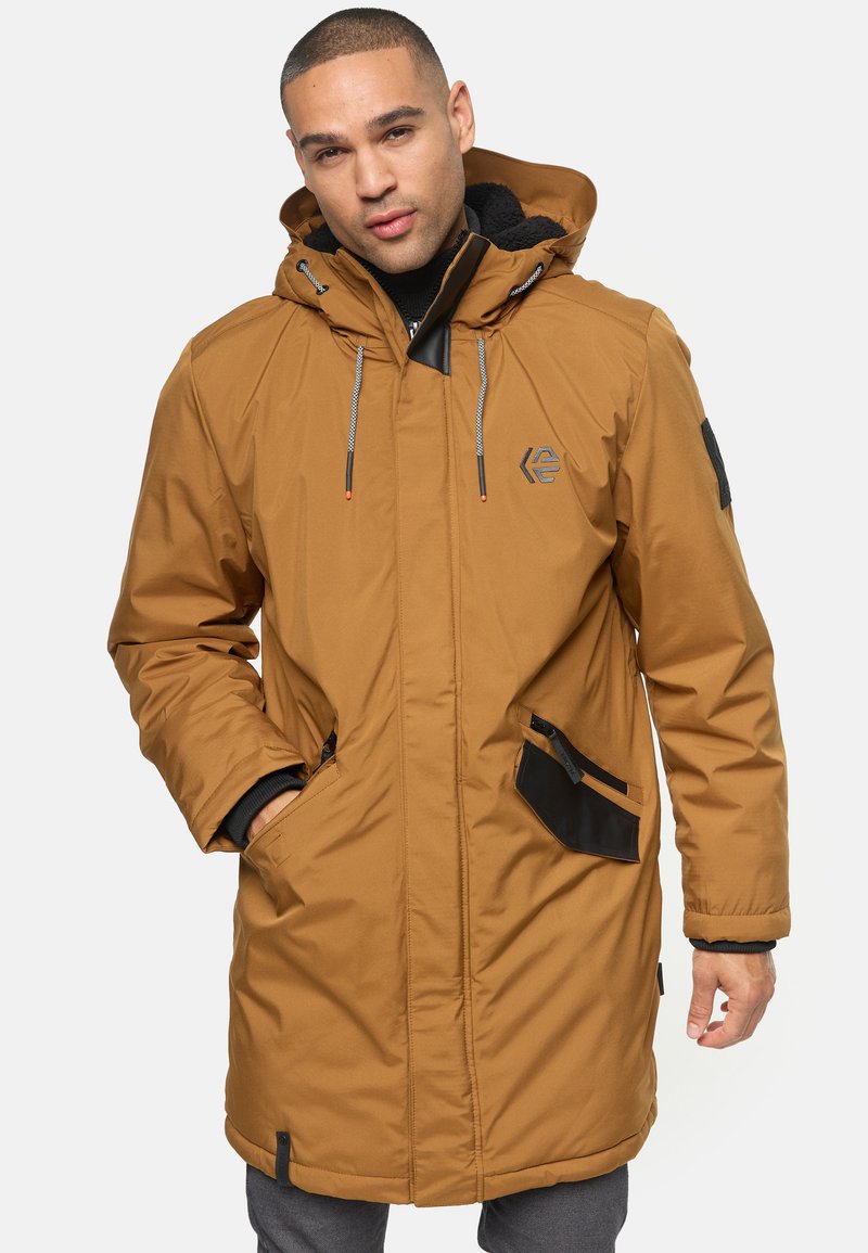 Parka marrón aislante con capucha, acentos negros, dos bolsillos frontales y cordones para ajuste. Presenta un logo en el pecho.