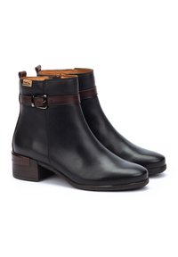 Botas de cuero negras hasta el tobillo con punta redondeada, detalle de correa y hebilla de cuero marrón, tacón bajo tipo bloque y forro interior color tostado.