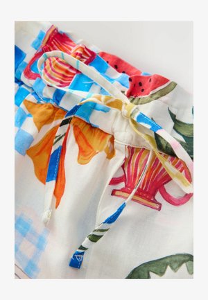White fabric with colorful floral and fruit patterns, featuring a gathered waistband with a contrasting drawstring and decorative accents.