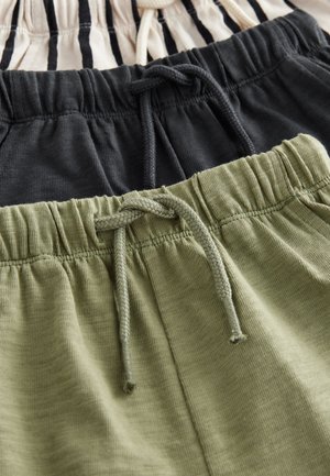 Trois paires de shorts sont étalées à plat : une paire beige avec des rayures noires, une paire entièrement noire, et une paire verte. Toutes disposent de tailles élastiques et de cordons de serrage.