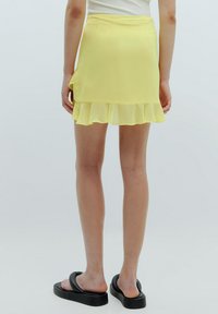 Geel chiffon mini rok met een gelaagde rand, voorzien van een gladde textuur en een strakke taille. Draag met zwarte sandalen.