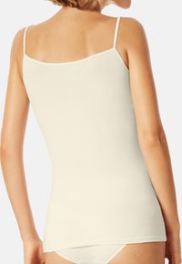 Light beige sleeveless tank top made from cotton. Features a fitted design, smooth texture, and adjustable thin straps.